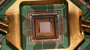 D-Wave TwoX 1000 Qubit quantum annealing processor chip mounted and wire-bonded in its sample holder.