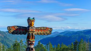 Totem pole towers over scenic wilderness and ocean in British Columbia, Canada. First Nations